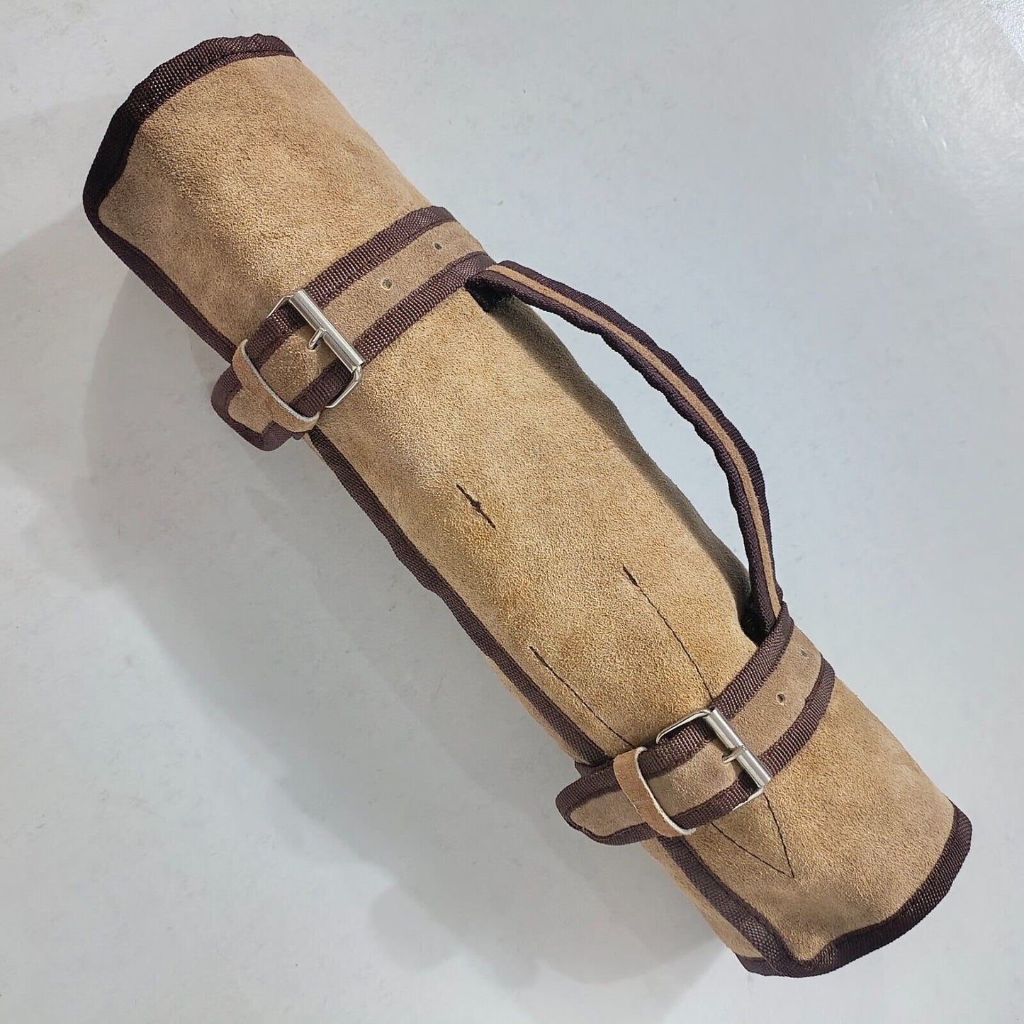 Professional 5 piece Damascus chef knife set and leather carrying roll displayed on a rustic wood surface.