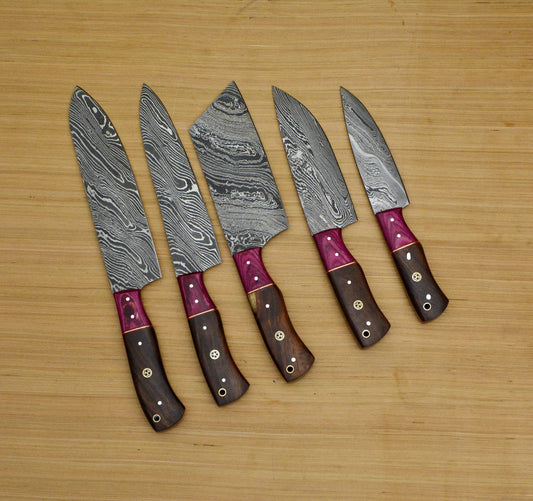 Five piece Damascus chef knife set with mosaic pin handles displayed on a wooden surface