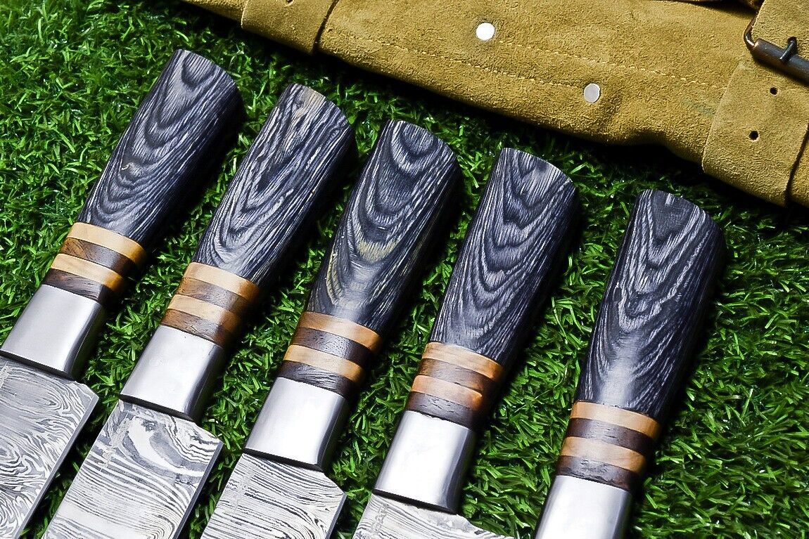 Close up of a Damascus chef knife handle showing the premium handmade steel bolster and intricate wood grain.