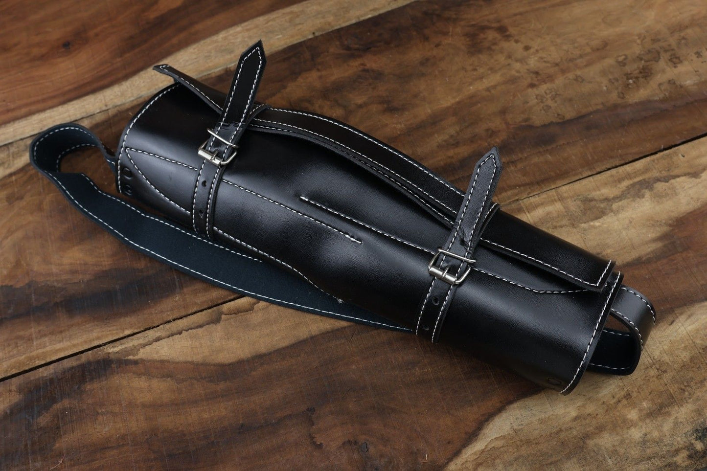 Professional Damascus steel knife collection including custom leather sheaths, displayed on a rustic outdoor surface, highlighting rugged bushcraft design.