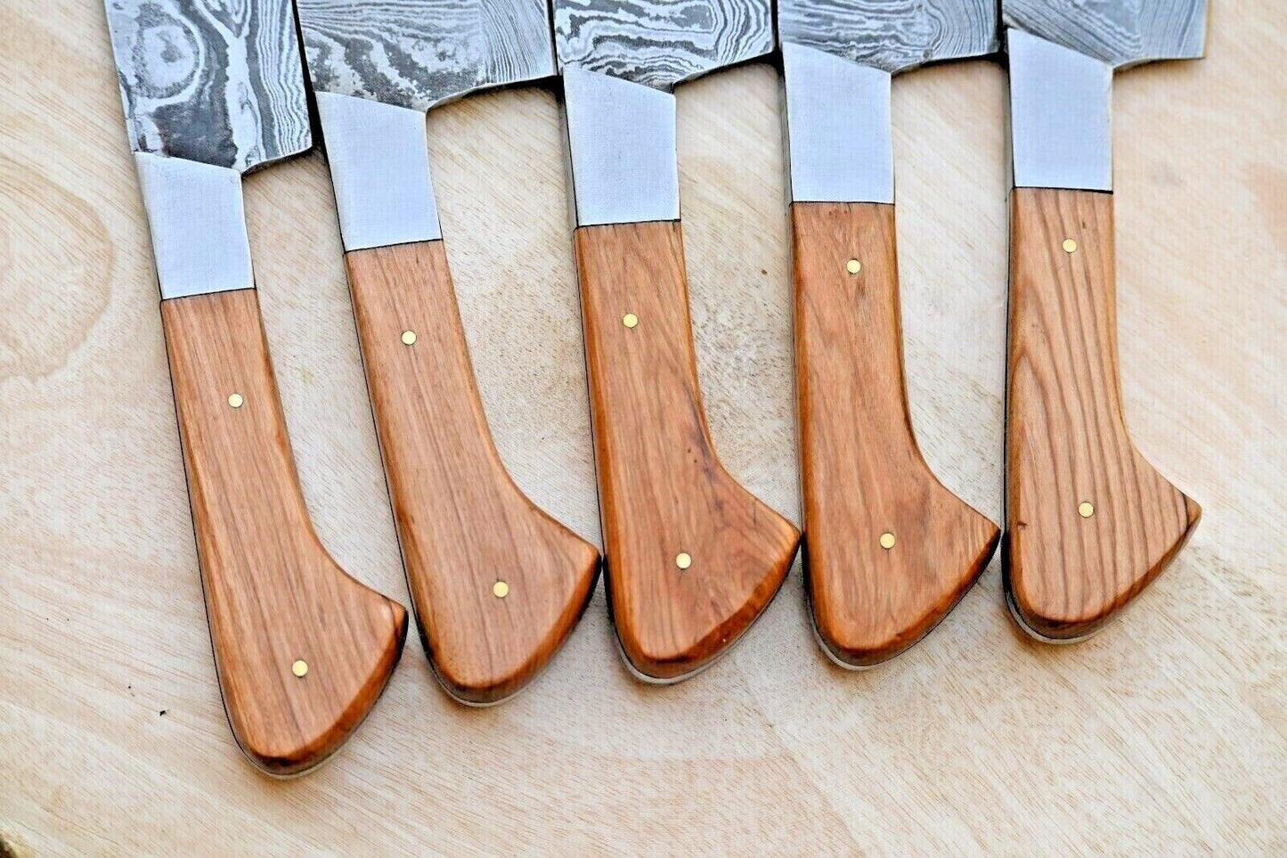Closeup of ergonomic wood handle and durable steel bolster on a custom forged Damascus kitchen knife.