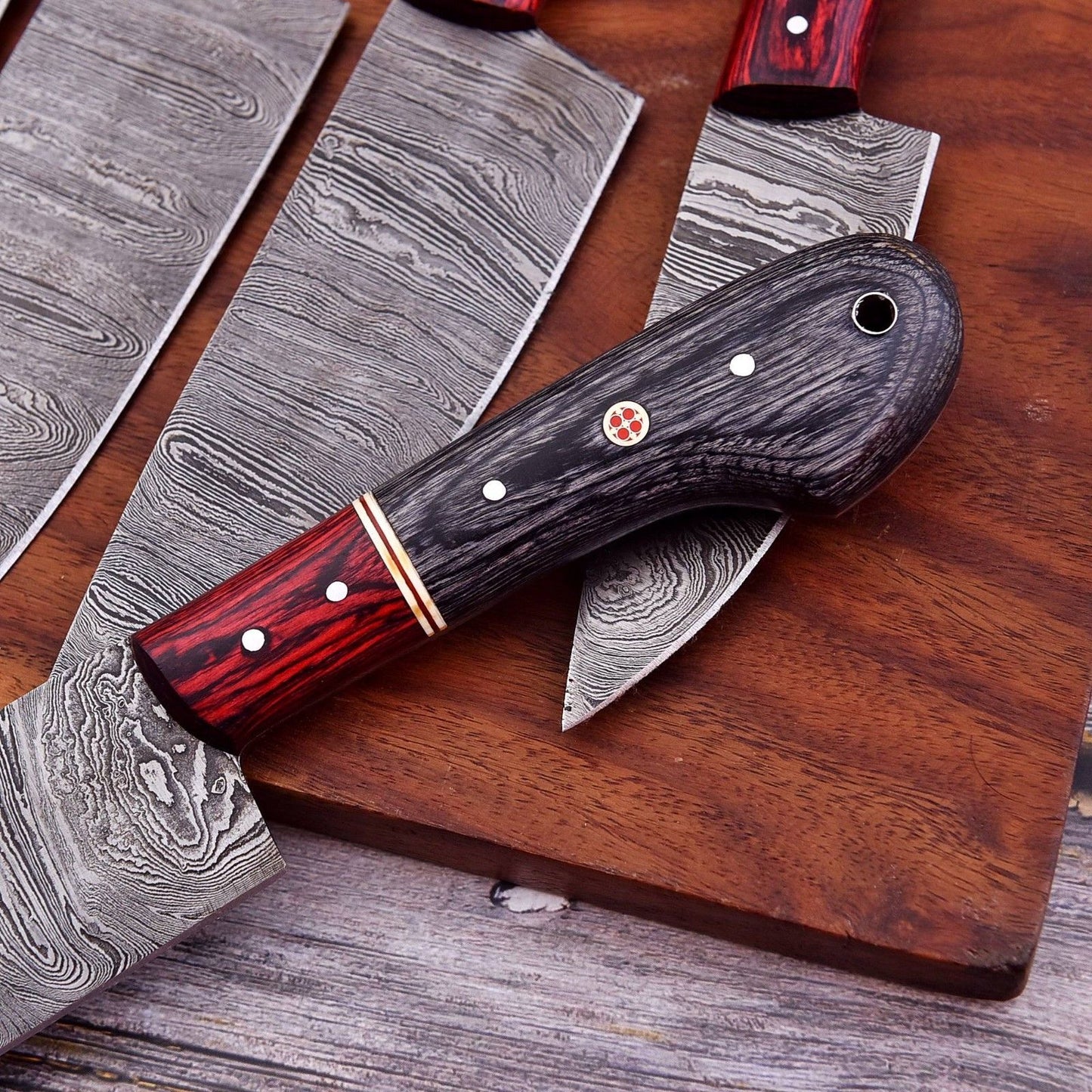 Hand forged Damascus steel kitchen knife collection displayed on a rustic surface, showcasing unique blade patterns and artisanal bone handles.