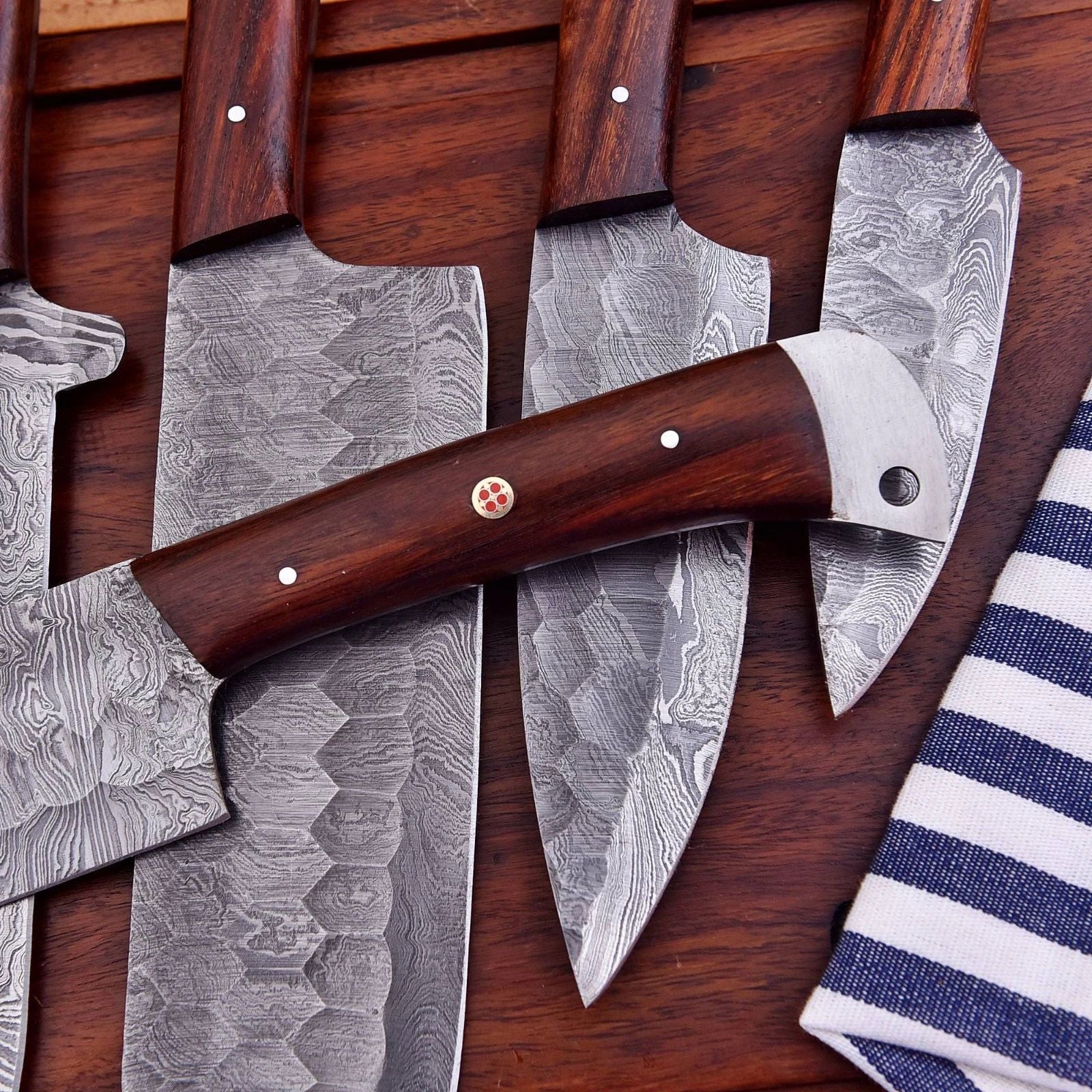 Close up detail of a hand forged Damascus steel chef knife showing the unique, wavy high carbon steel pattern and sharp cutting edge.