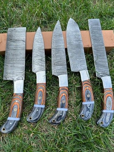 Complete 5 pieces custom Damascus kitchen knife set with wooden handles on rustic wood background.