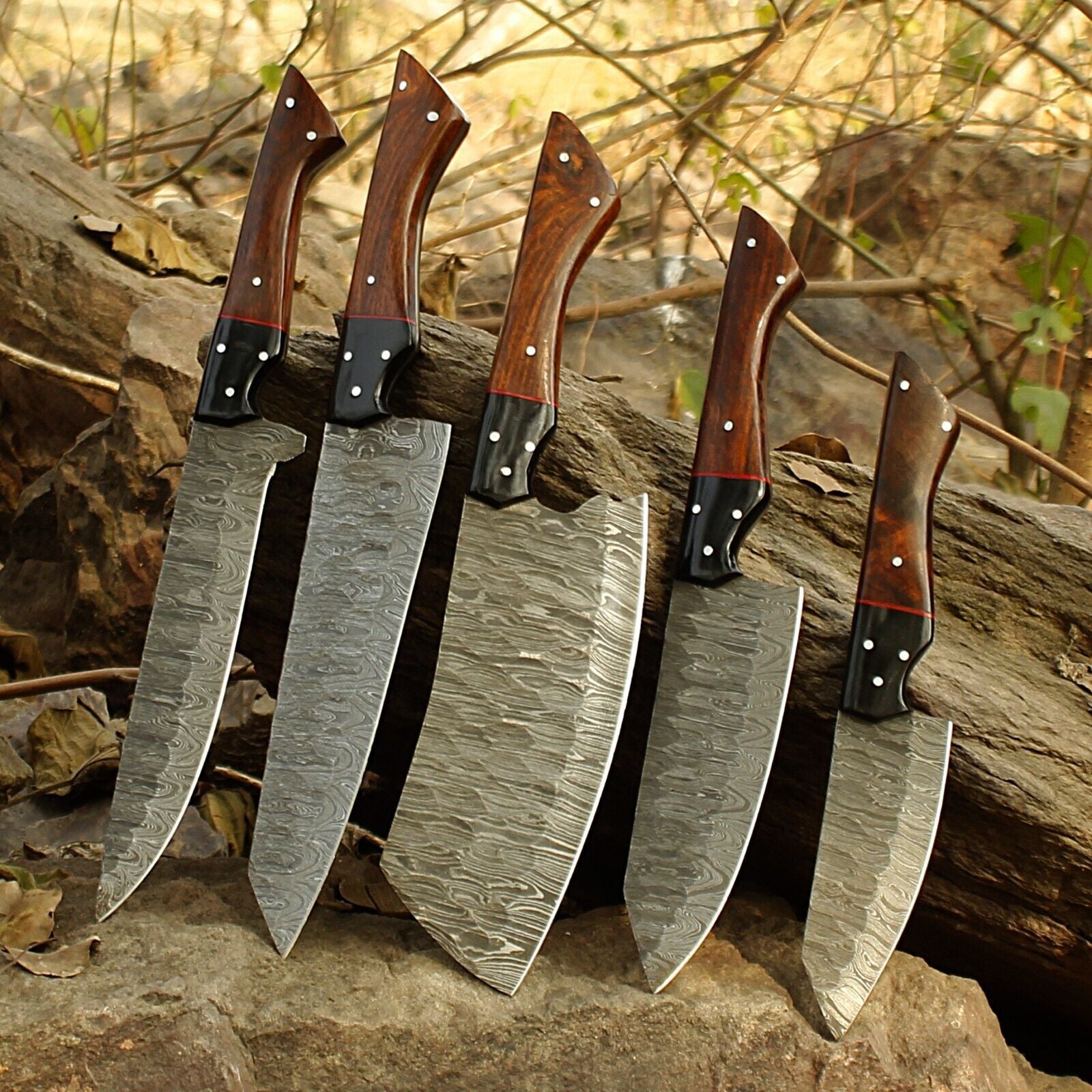 Top down view of a 5 pieces Damascus steel kitchen knife set highlighting the hand ground edges and custom craftsmanship.
