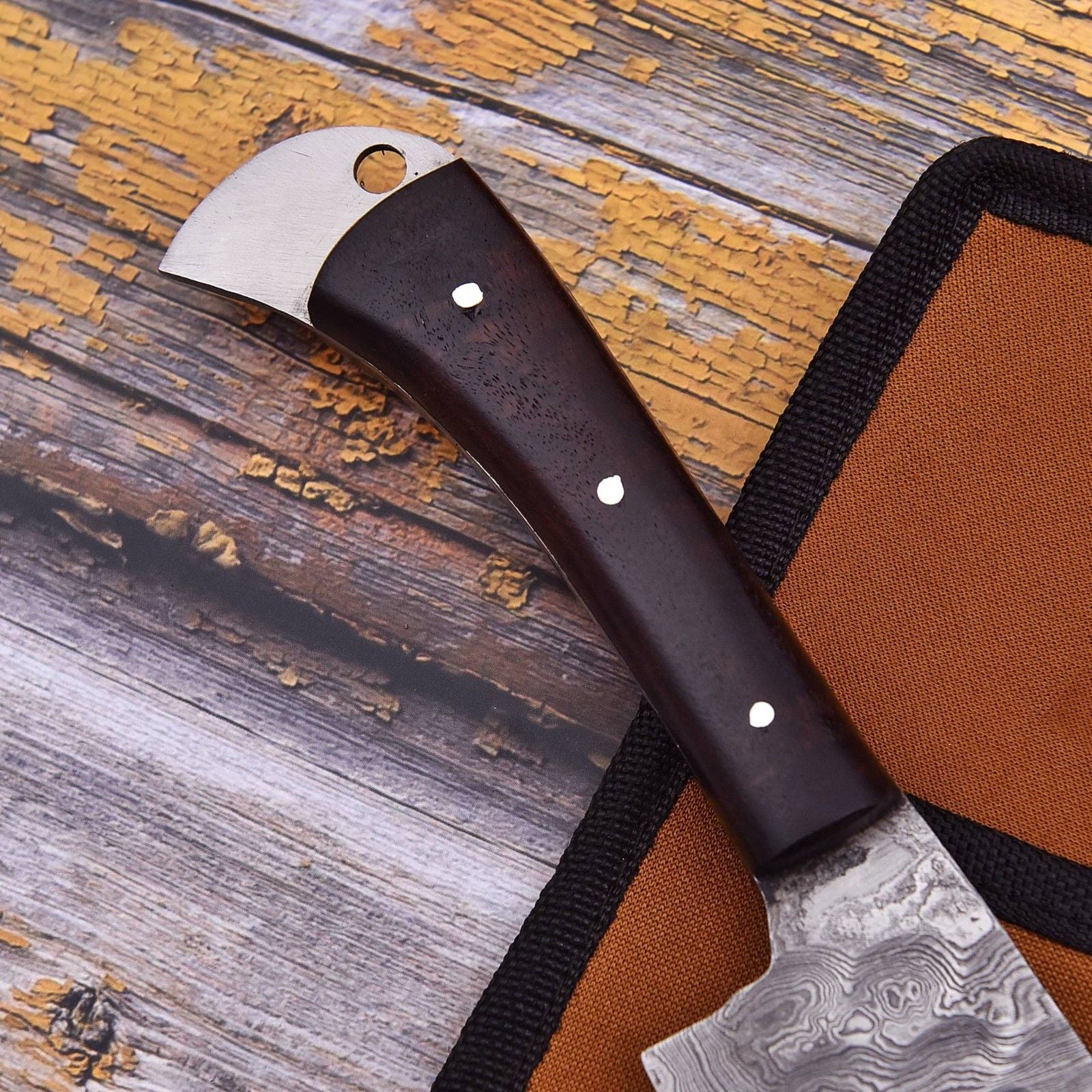 Close up of a professional Damascus chef knife handle crafted from natural wood, showcasing detailed mosaic pins and a comfortable, sturdy grip.