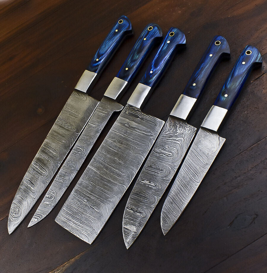 Handmade Damascus steel kitchen knives resting on a natural wood surface, highlighting professional culinary craftsmanship.