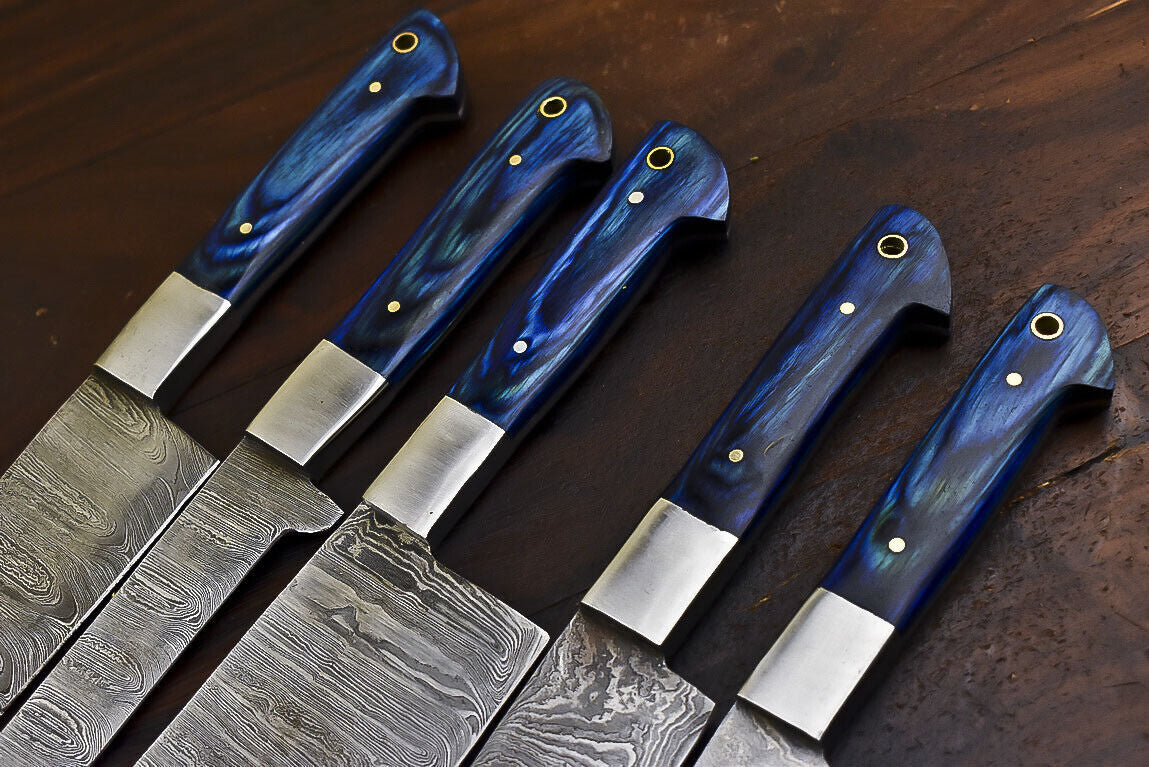 Detailed view of ergonomic hardwood knife handle and polished steel bolster on a handmade Damascus chef knife.