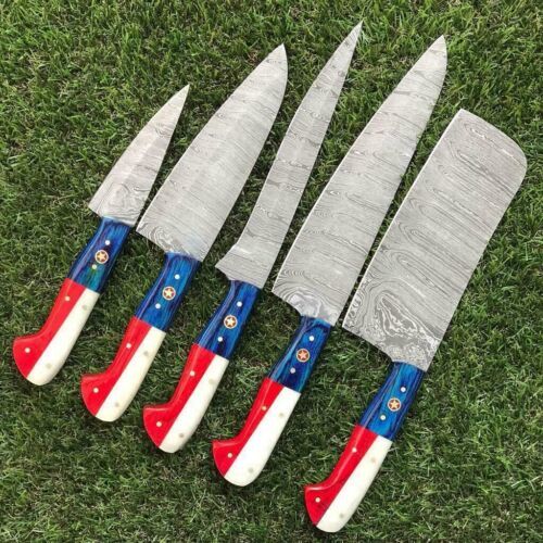 Hand forged Damascus steel clip point blade on a handmade kitchen knife, shown on a rustic outdoor setting.