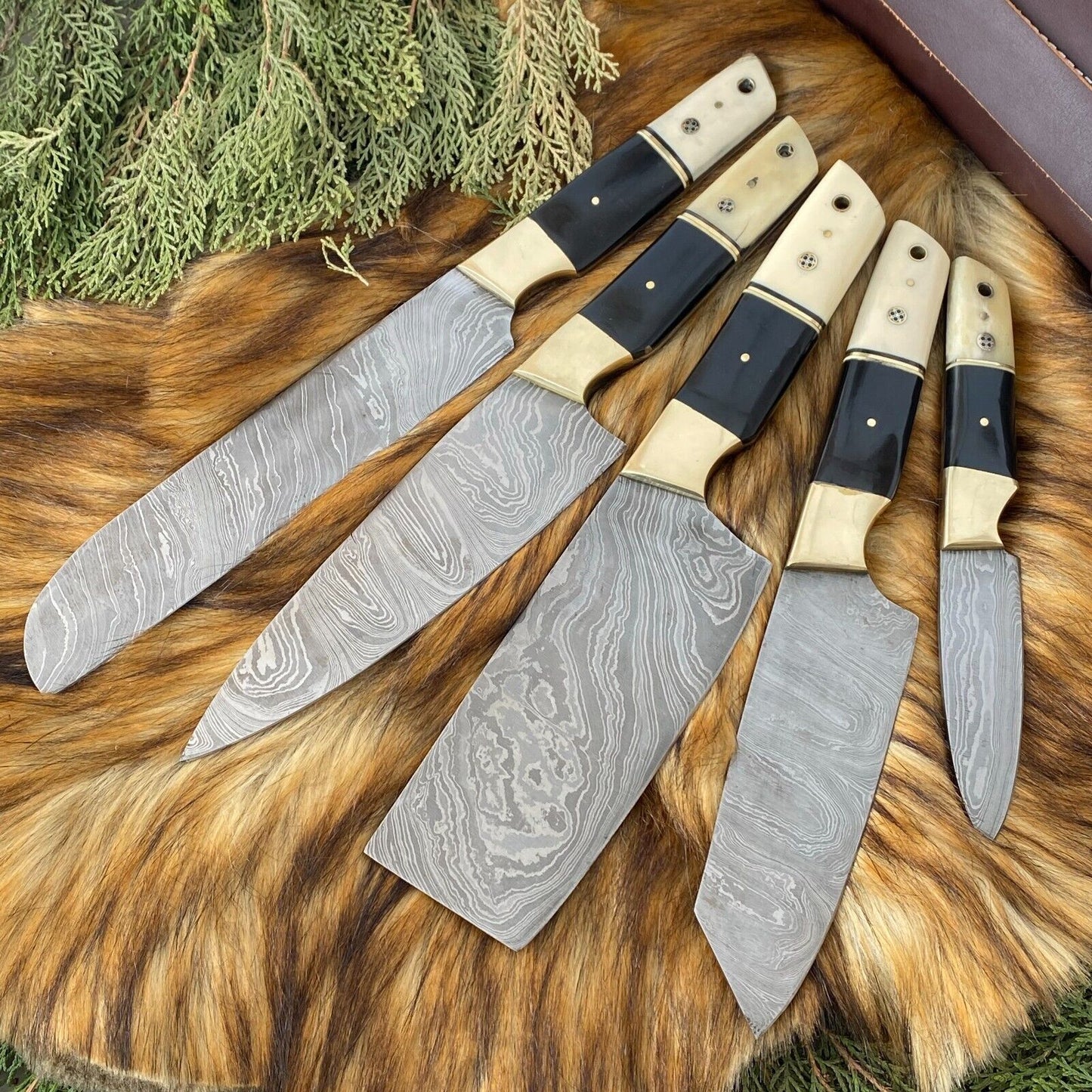 Detailed view of custom kitchen knife with sleek black coated steel blade and artisanal bone and horn handle.