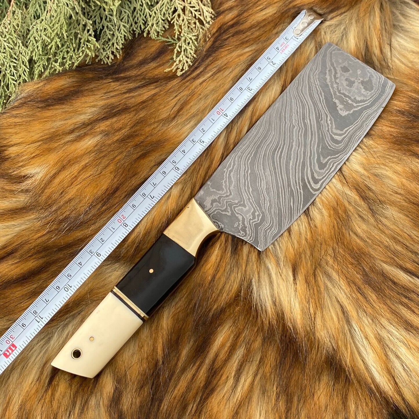 Detailed view of custom kitchen knife with sleek black coated steel blade and artisanal bone and horn handle.