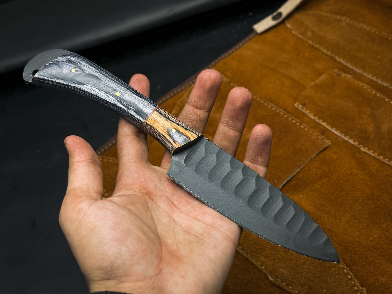 Close up of a rugged gray carbon steel drop point blade with a clean, plain edge finish.