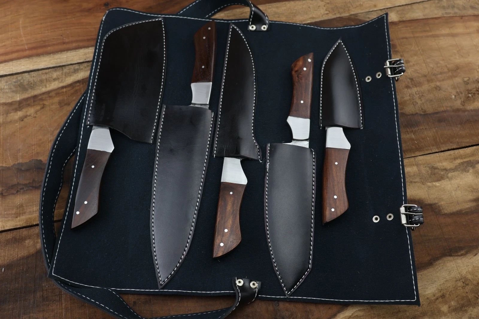 Professional Damascus steel kitchen knife collection with custom leather sheaths, showcasing rugged artisanal design and high quality materials.