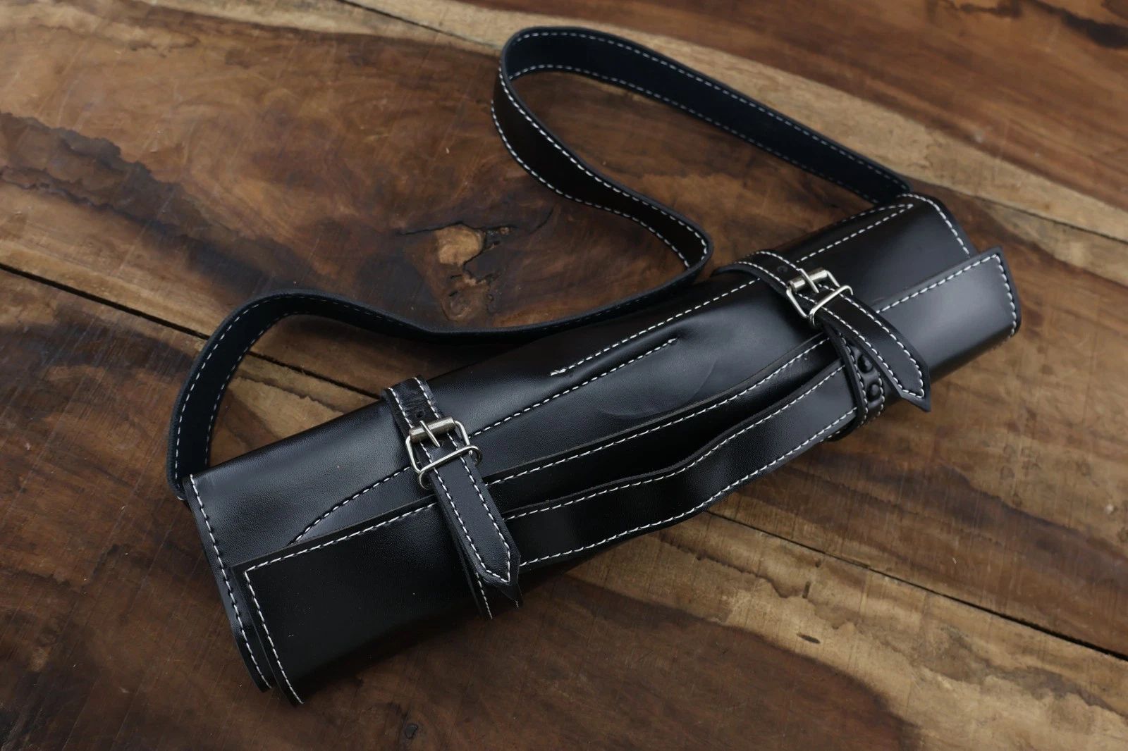 Hand stitched leather roll containing a 5 piece handmade Damascus steel chef knife set with premium hardwood handles and brass mosaic pins.