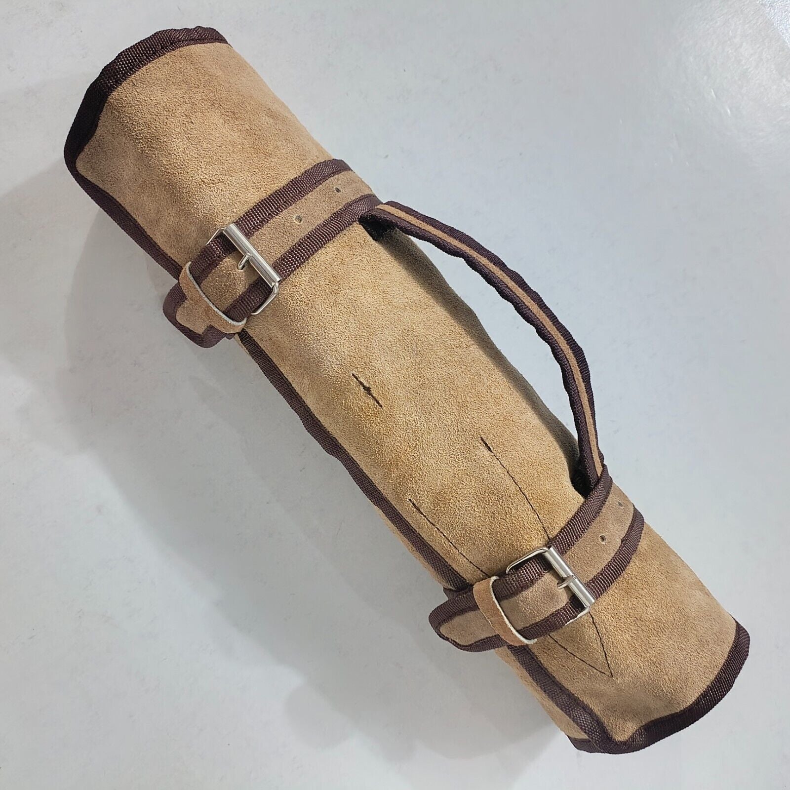 Professional 5 piece Damascus chef knife set and leather carrying roll displayed on a rustic wood surface.
