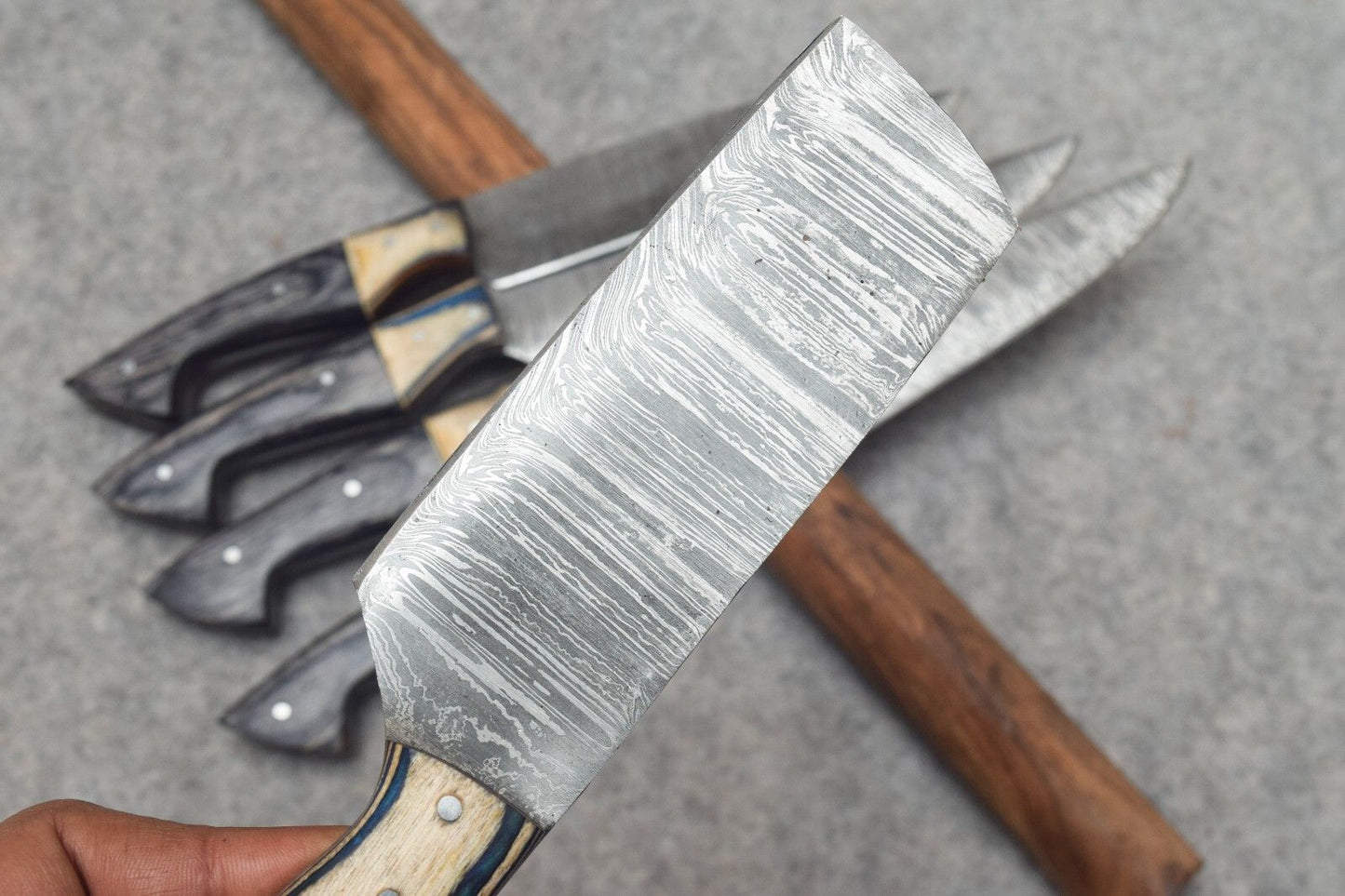 Detailed view of hand forged Damascus steel blade pattern on a professional kitchen chef knife, showcasing artisanal craftsmanship.
