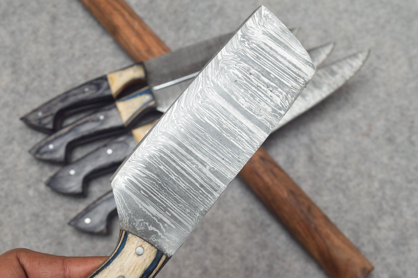 Detailed view of hand forged Damascus steel blade pattern on a professional kitchen chef knife, showcasing artisanal craftsmanship.