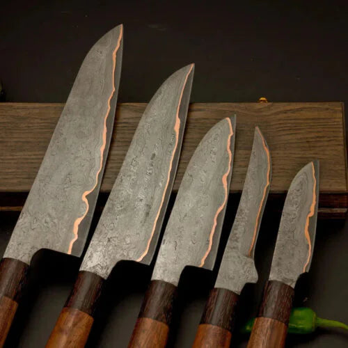 Close up view of 5 pieces Damascus steel chef knife blades with distinct patterns displayed on a wooden stand