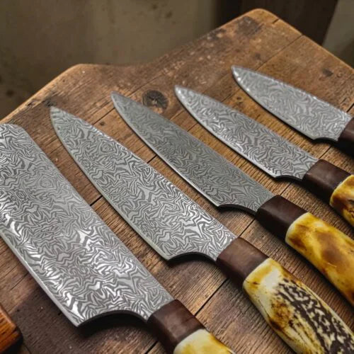 Overhead view of 5 pcs Damascus steel kitchen knives with ergonomic antler handles arranged on a wooden board