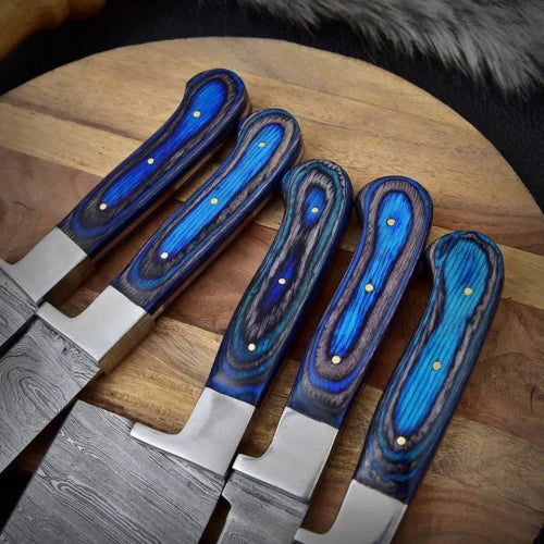 Professional chef knife set handles and hammered Damascus steel blades displayed on a wooden surface