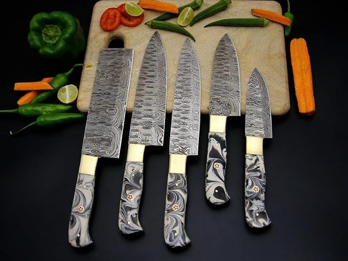 Damascus steel chef knives with marbled acrylic handles arranged on a cutting board with peppers and carrots