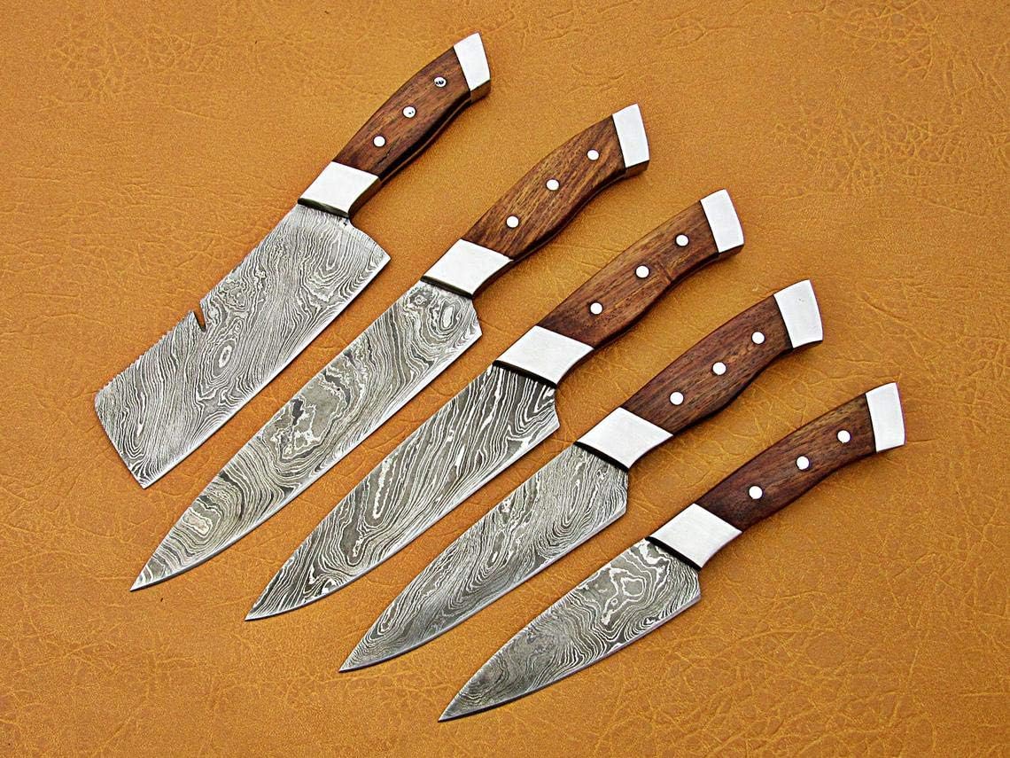 5 Pcs Damascus Steel Chef Knife Set with cleaver, chef, utility and paring knives laid diagonally on tan leather