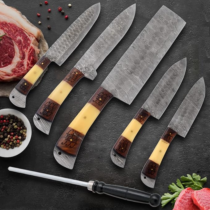 Damascus steel knife set with wood handles and a rod beside steak and herbs