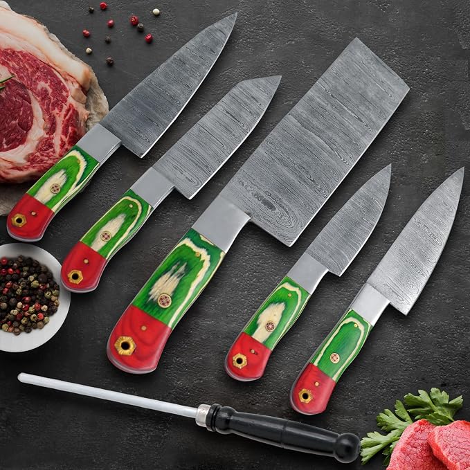 Damascus steel knife set with green and red pakka wood handles and a rod beside steak and peppercorns