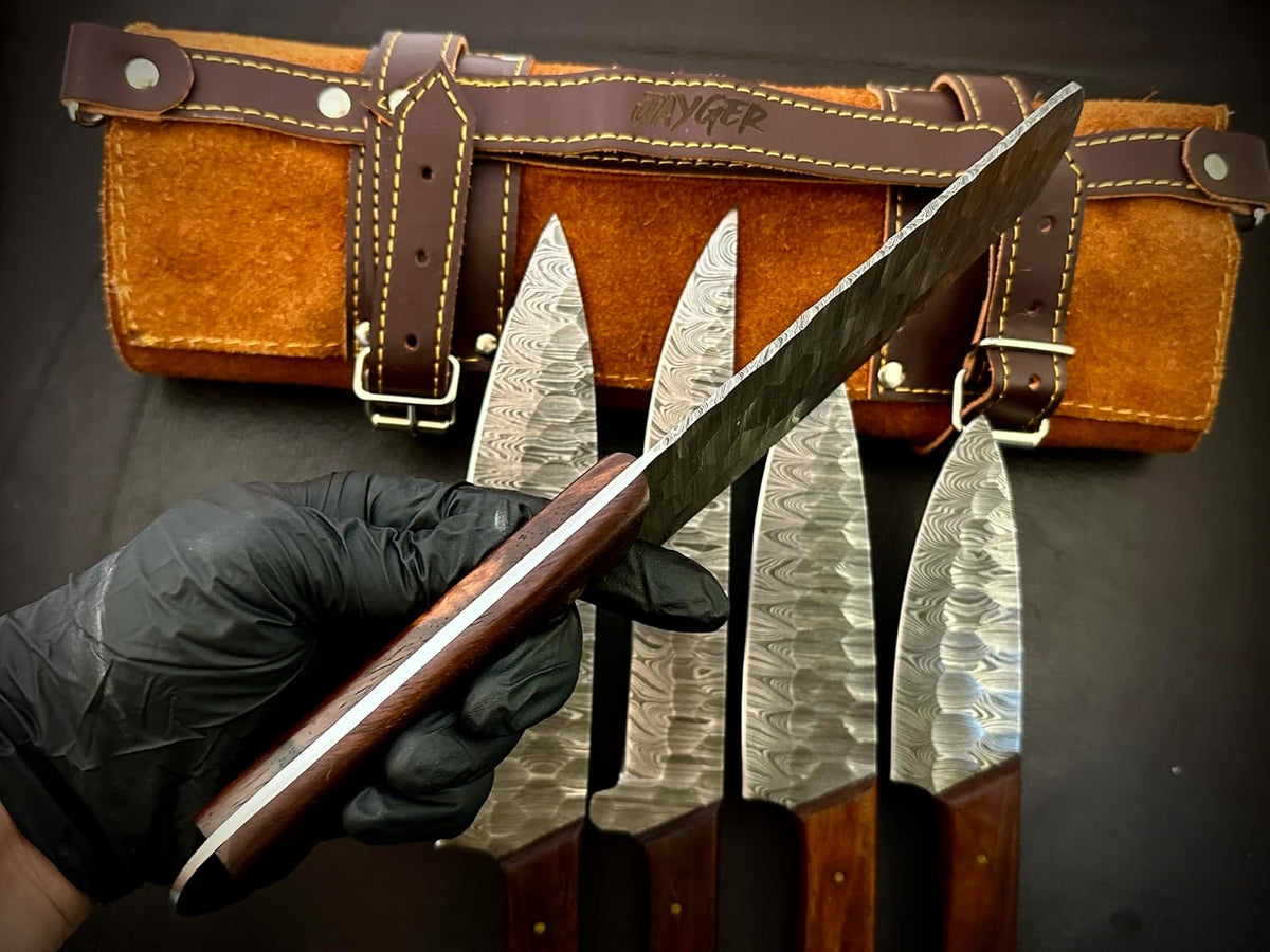 Hand holding a Damascus steel knife beside a leather roll case and other blades