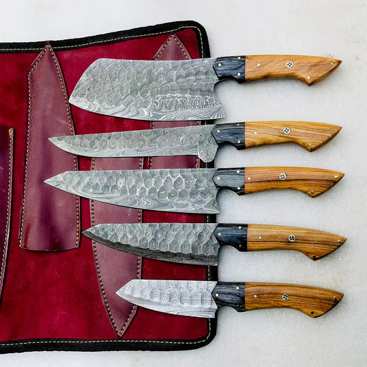 Damascus chef knife set of five laid across an open burgundy leather knife roll
