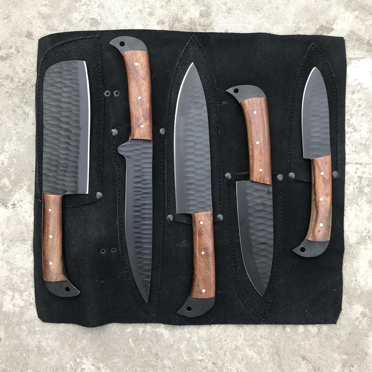 Black kitchen knife set of five with rosewood handles laid out on an open knife roll