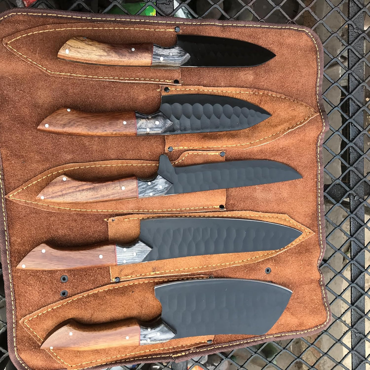 Kitchen knife set of five laid in a row with rosewood handles and black blades