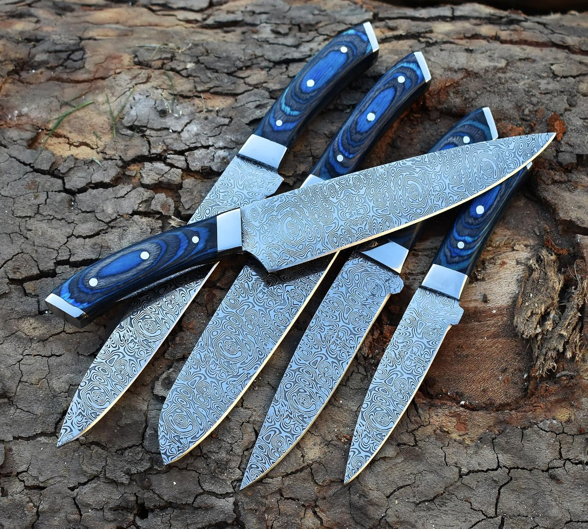 Kitchen knives with etched swirl blades fanned out across a tree stump