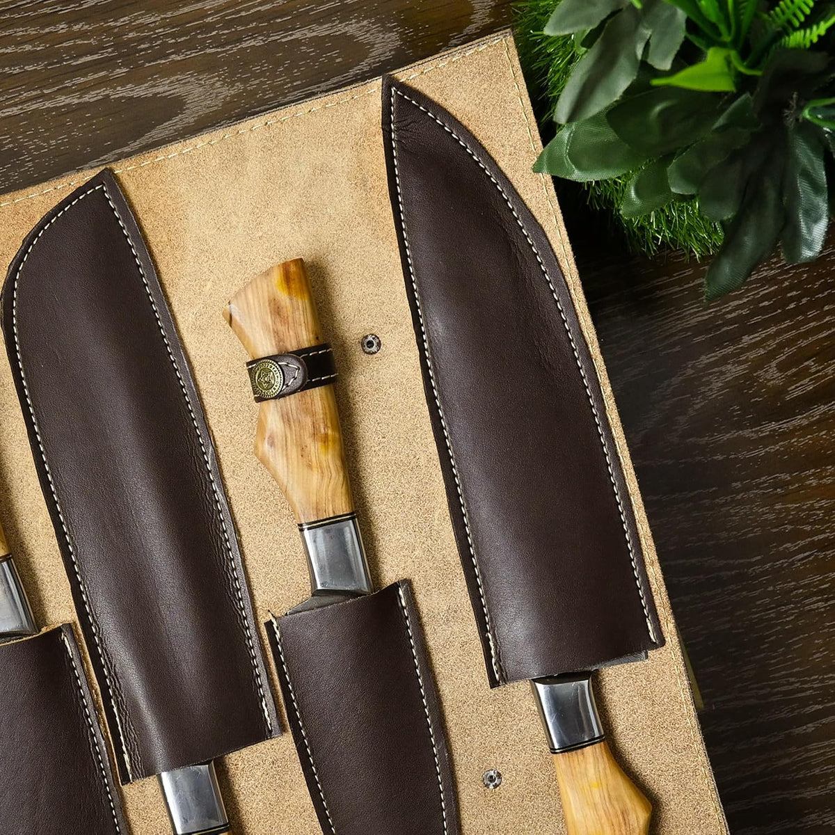 Open leather roll case showing individual sheaths and a pakka wood handle secured under a leather strap with snap stud