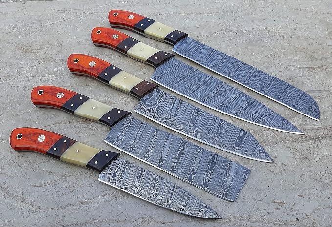 5 piece Damascus steel knife set with orange pakka wood and cream bone handles on a stone surface