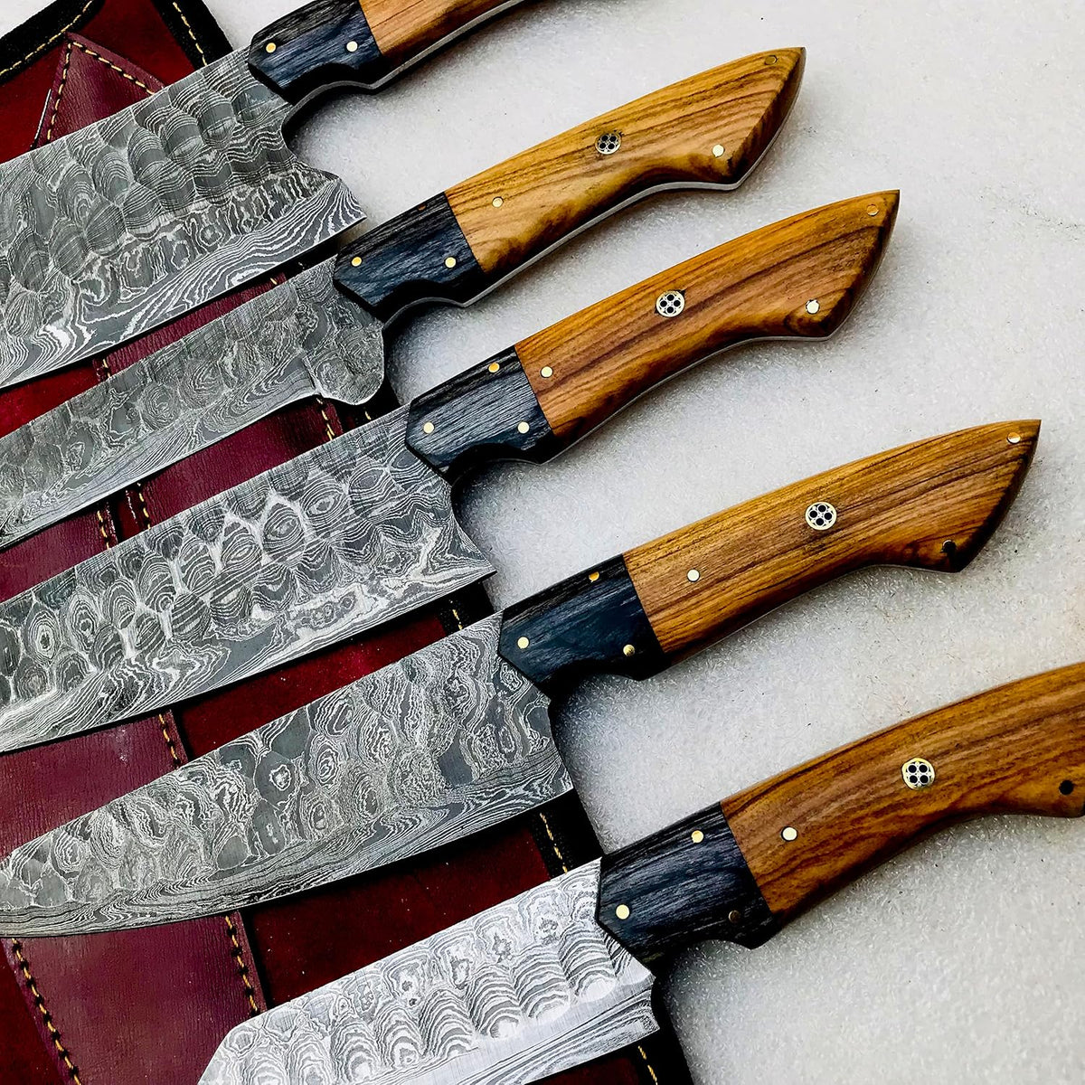 Damascus kitchen knife set of five with olive wood handles on a burgundy roll