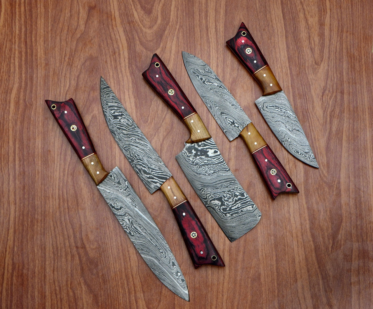 Damascus chef knife set with red pakka wood handles fanned on wood table