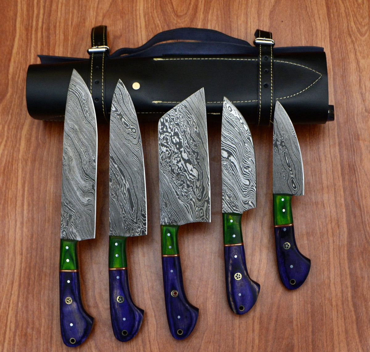 5 piece Damascus chef knife set with colorful handles displayed in front of a rolled black leather storage bag.