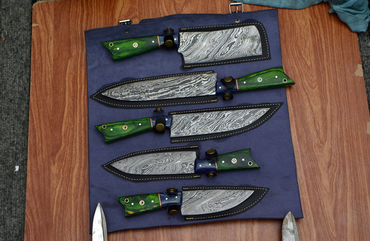 Damascus steel kitchen knife set with green pakka wood handles placed inside sheaths on a cloth roll