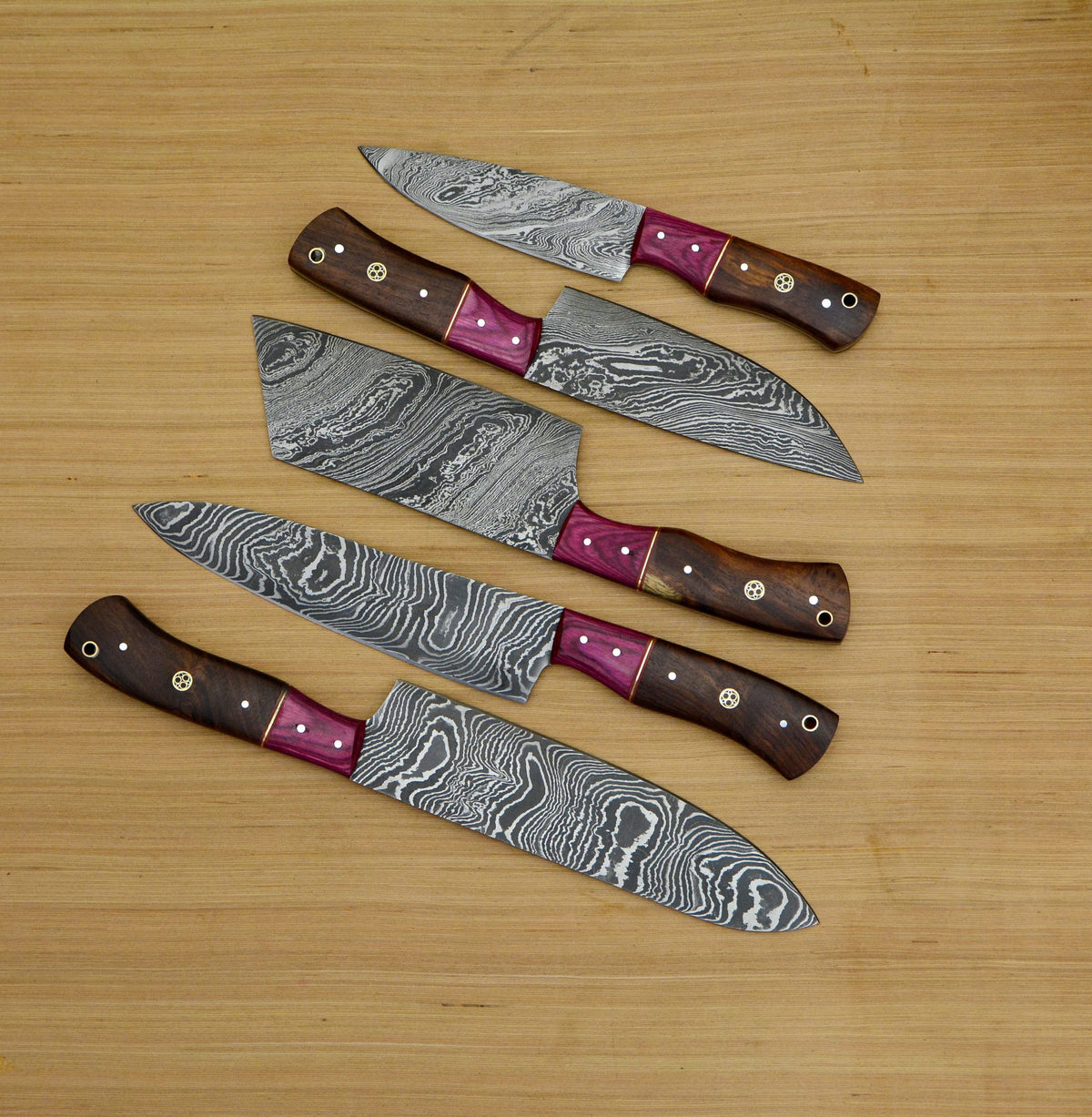 Five Damascus kitchen knives on wood.   