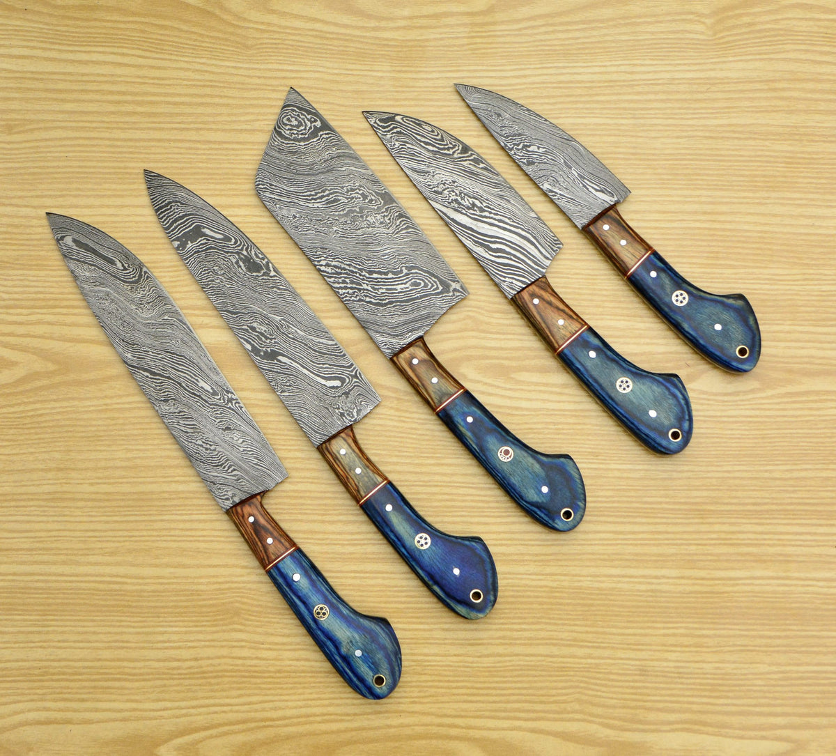 Blue pakka wood handle knives with copper liner fanned on wood table