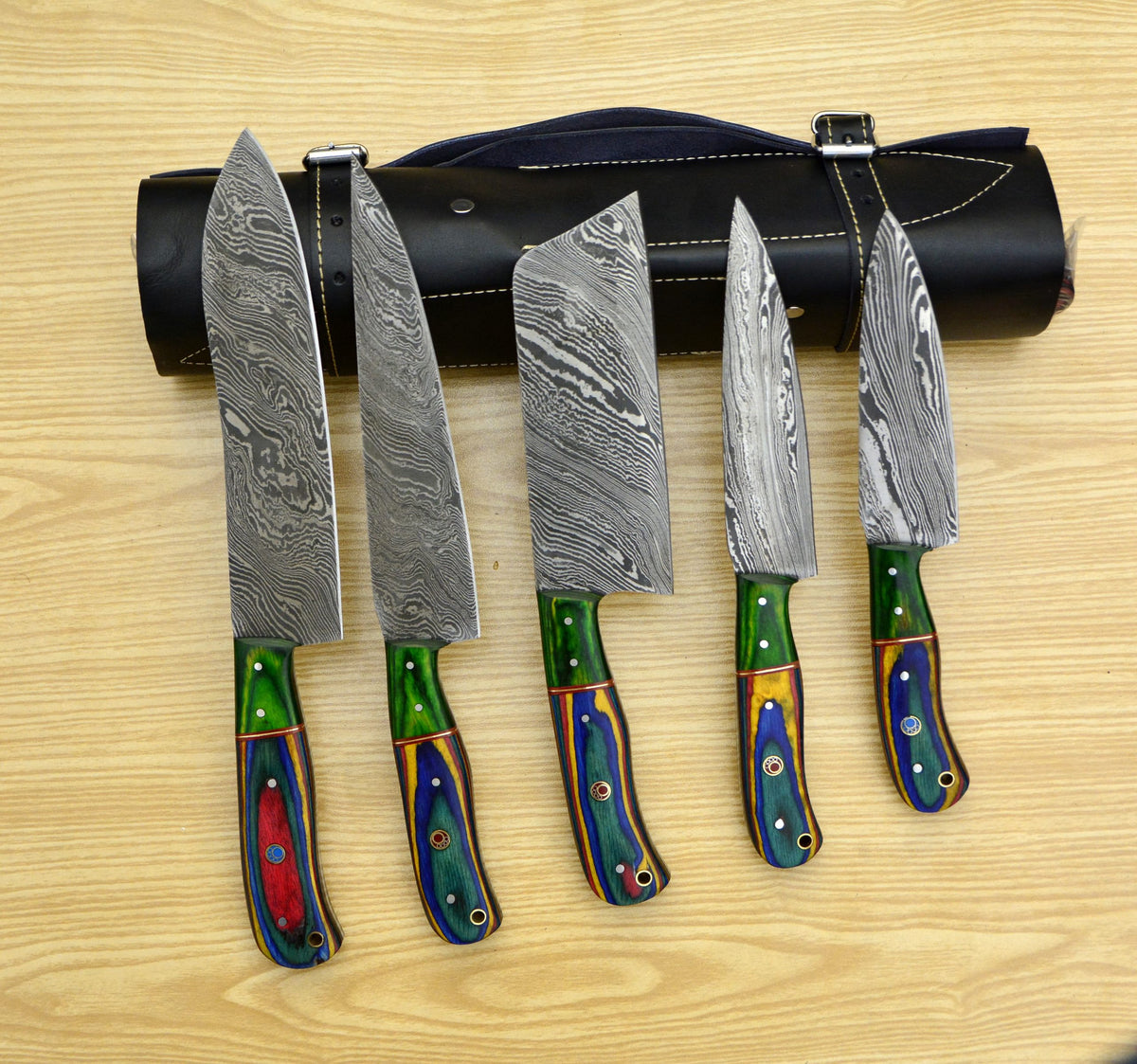 Multicolor pakka wood handle knives fanned out on wood table