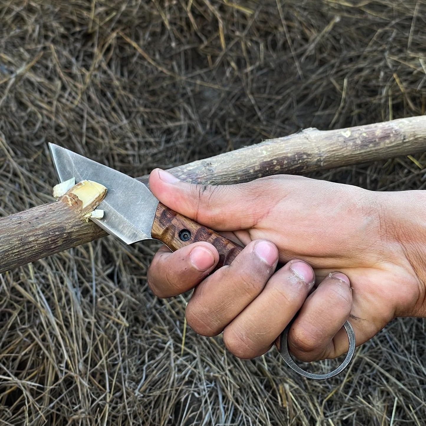 Best Bushcraft Knife being used to carve wood outdoors, held in hand with finger-ring grip