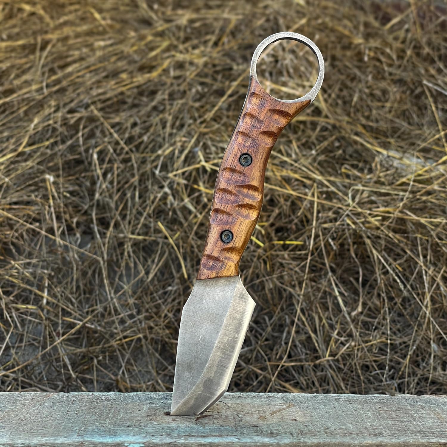 Best Bushcraft Knife standing upright in wooden beam with hay background