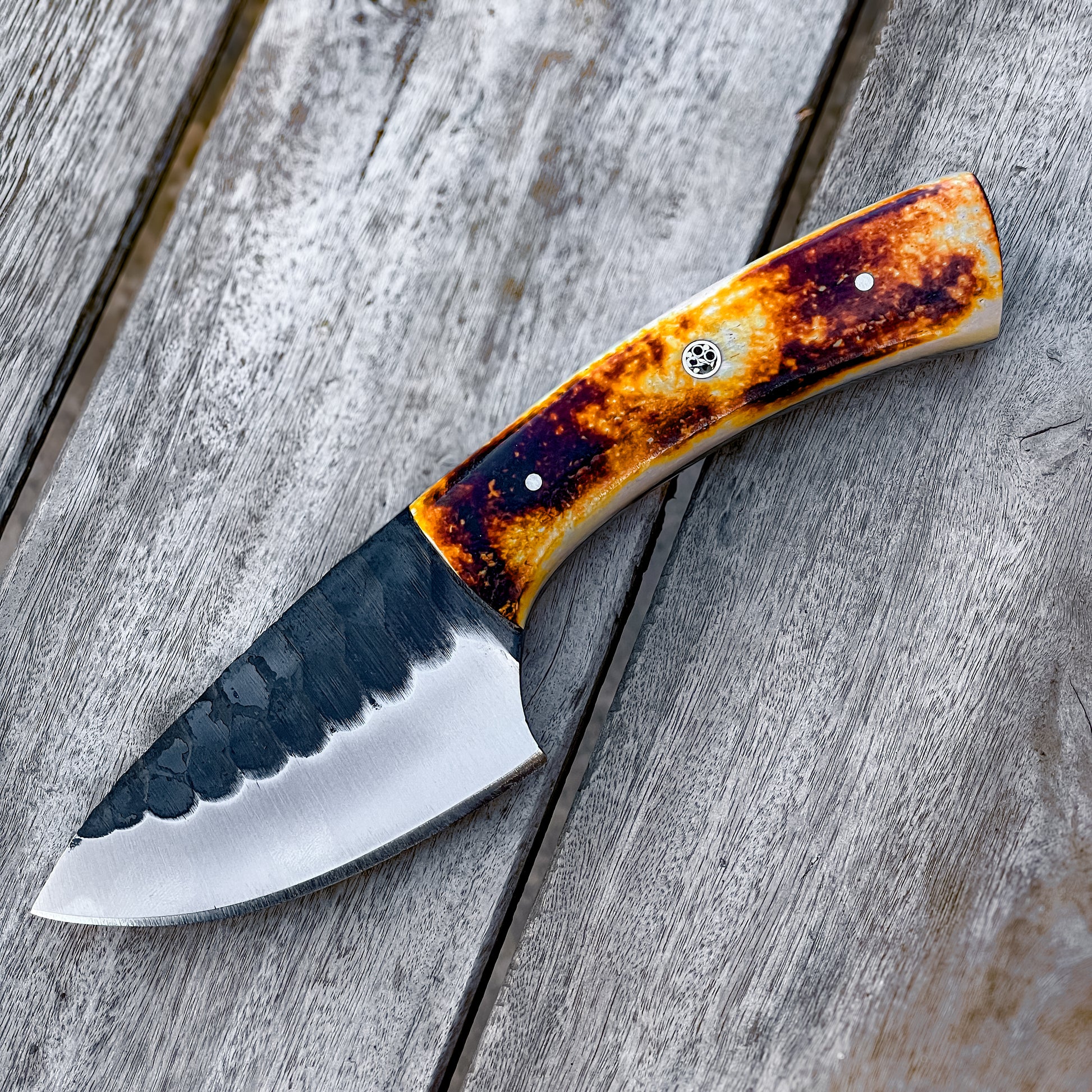 Bone Handle Skinner Knife with hammered blade and amber bone handle on wood plank