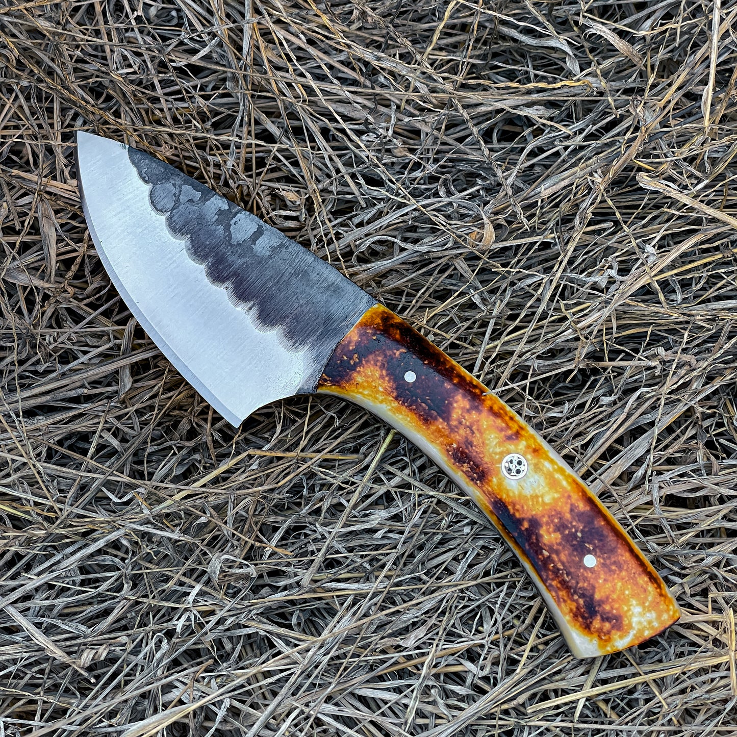Bone Handle Skinner Knife with hammered blade resting on dry hay