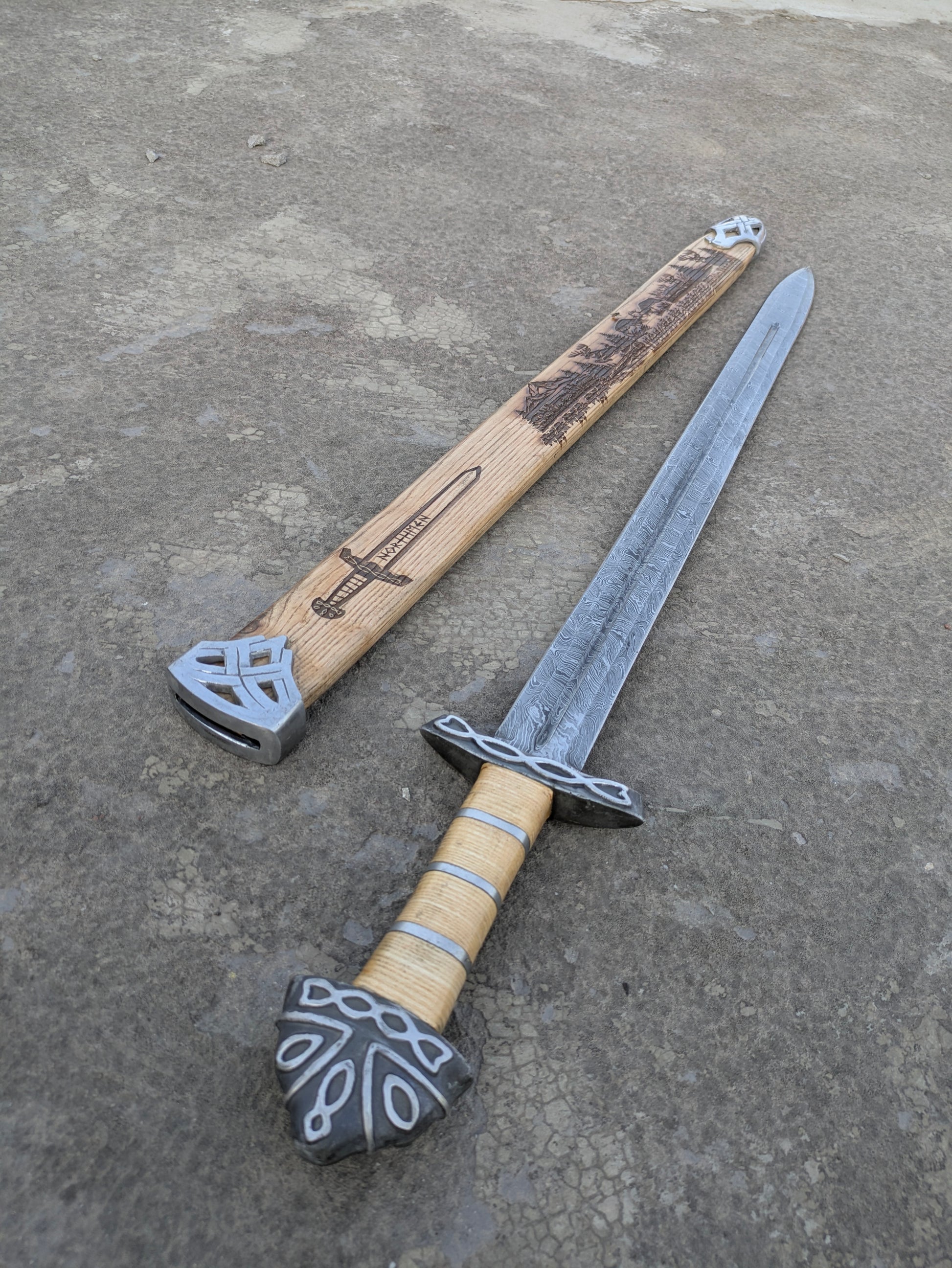 Damascus Steel Northman Viking Sword with wood grip beside Northmen engraved scabbard