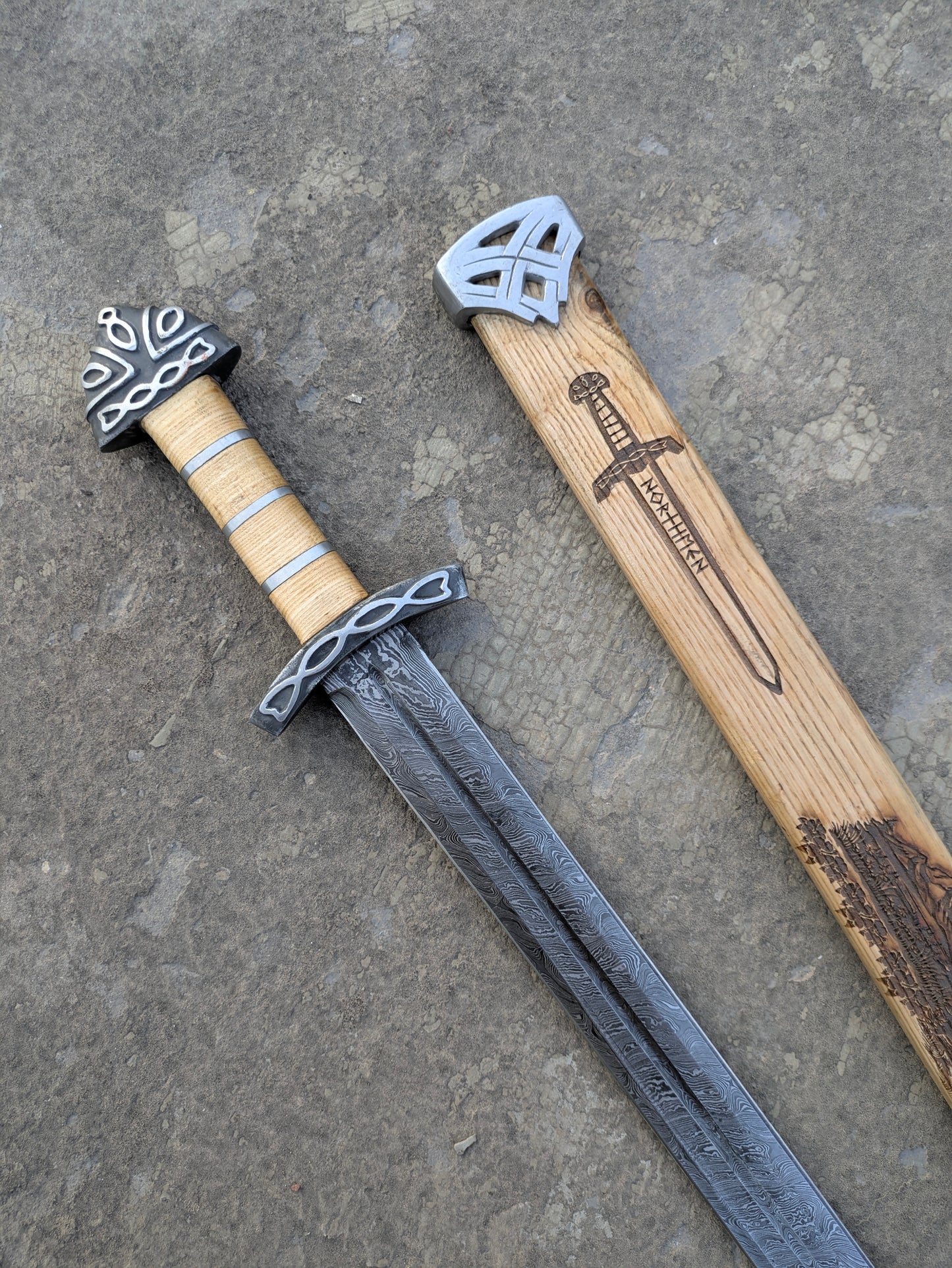 Damascus Steel Northman Viking Sword with wood grip beside engraved wooden scabbard