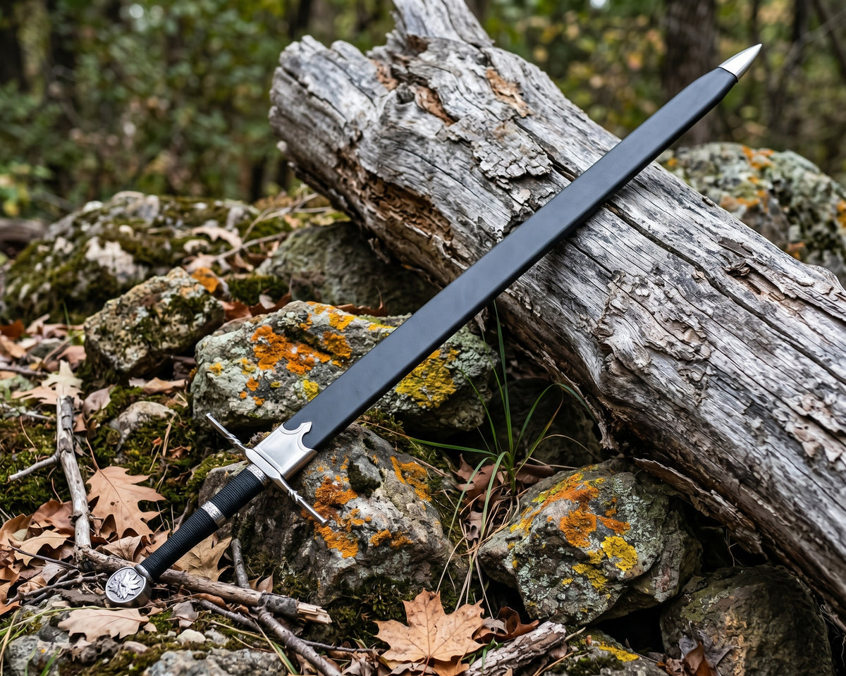 Decorative sword in a black sheath with silver tone throat and tip lying across mossy rocks and fallen leaves