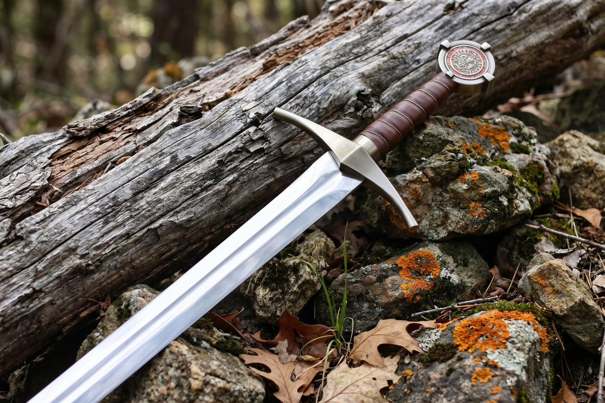 Close up of curved crossguard and polished grooved blade of a decorative sword on a mossy log